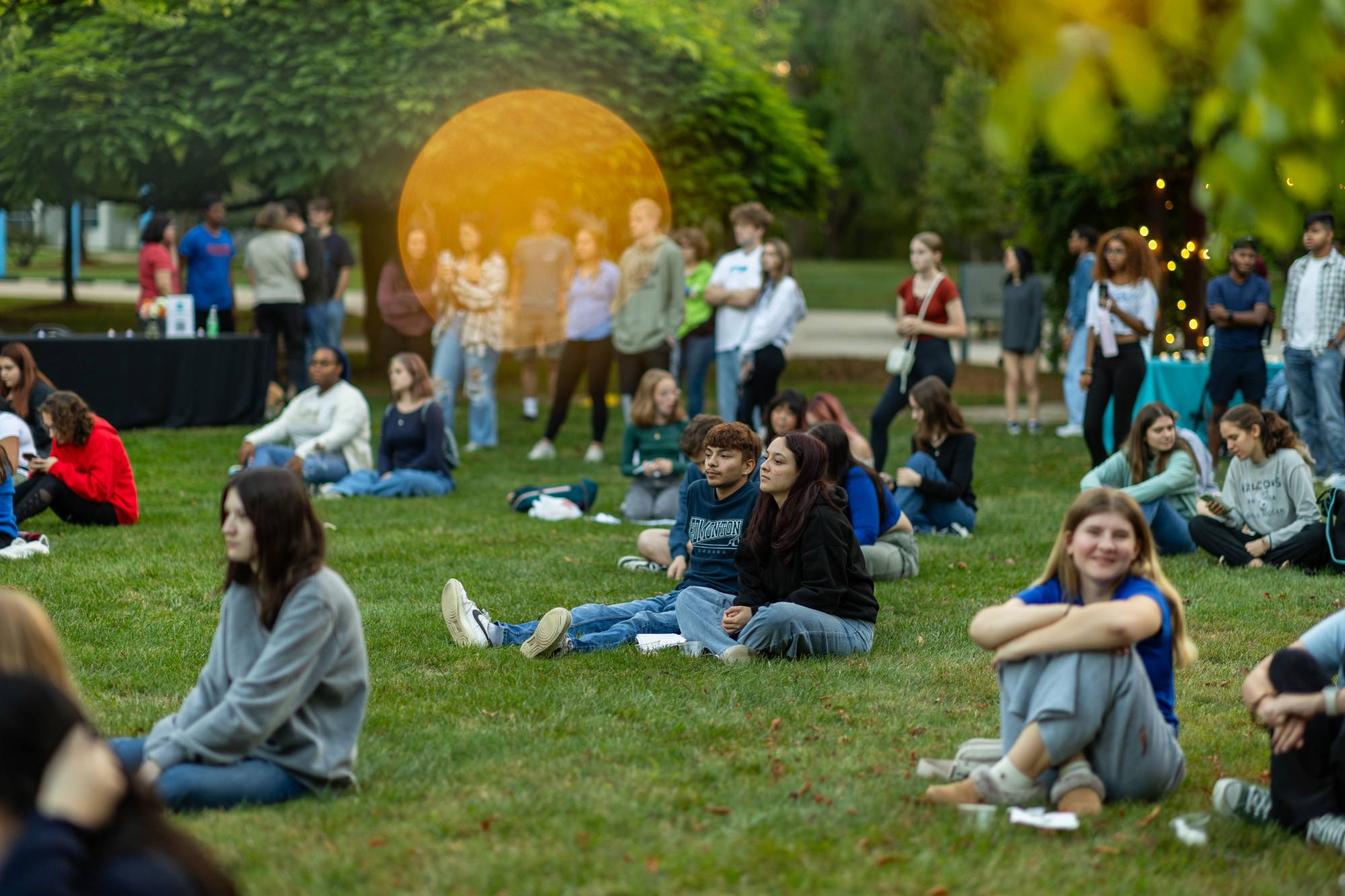 students sitting in the grass listening to music